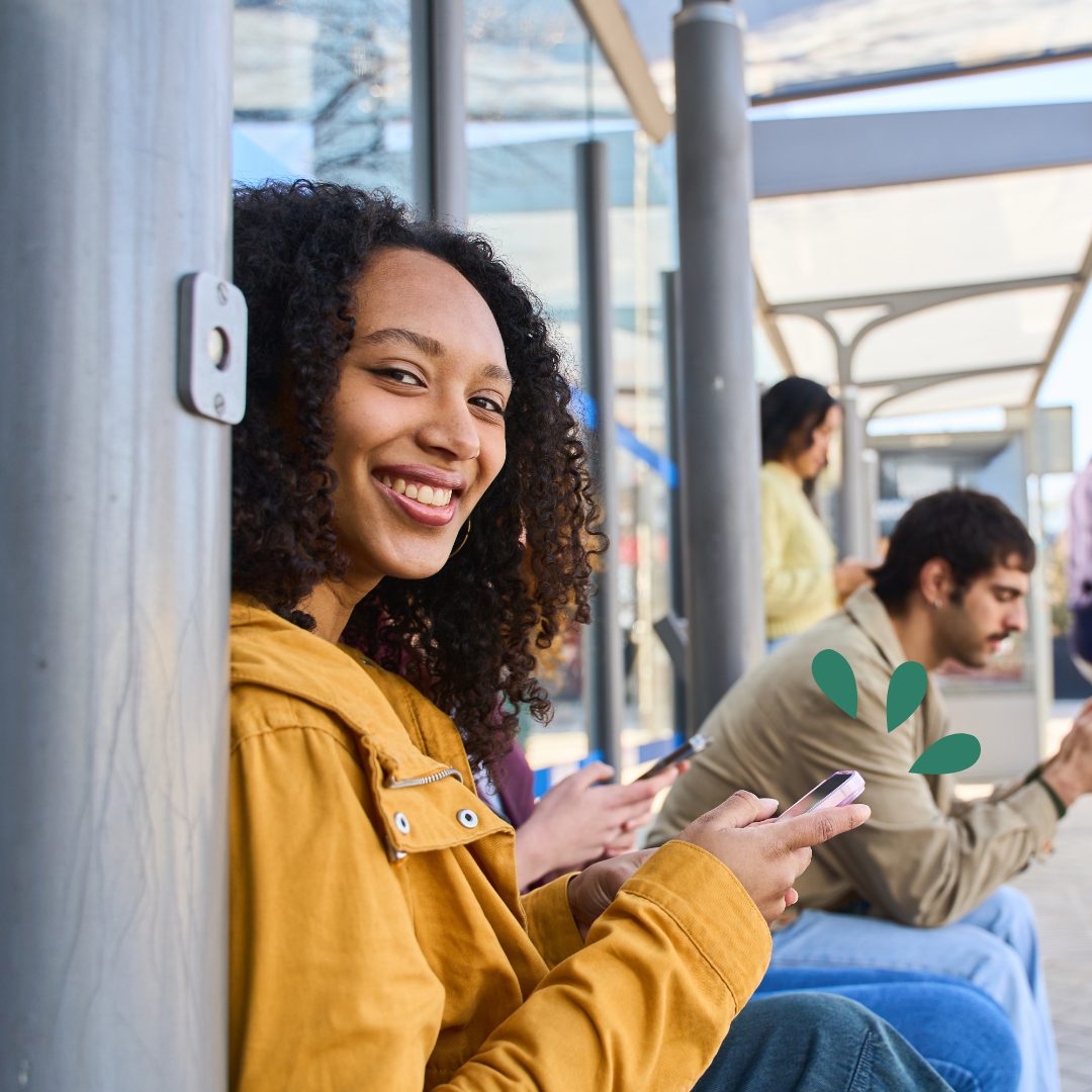 ITIN Loans Woman waiting at a bus stop with her phone out