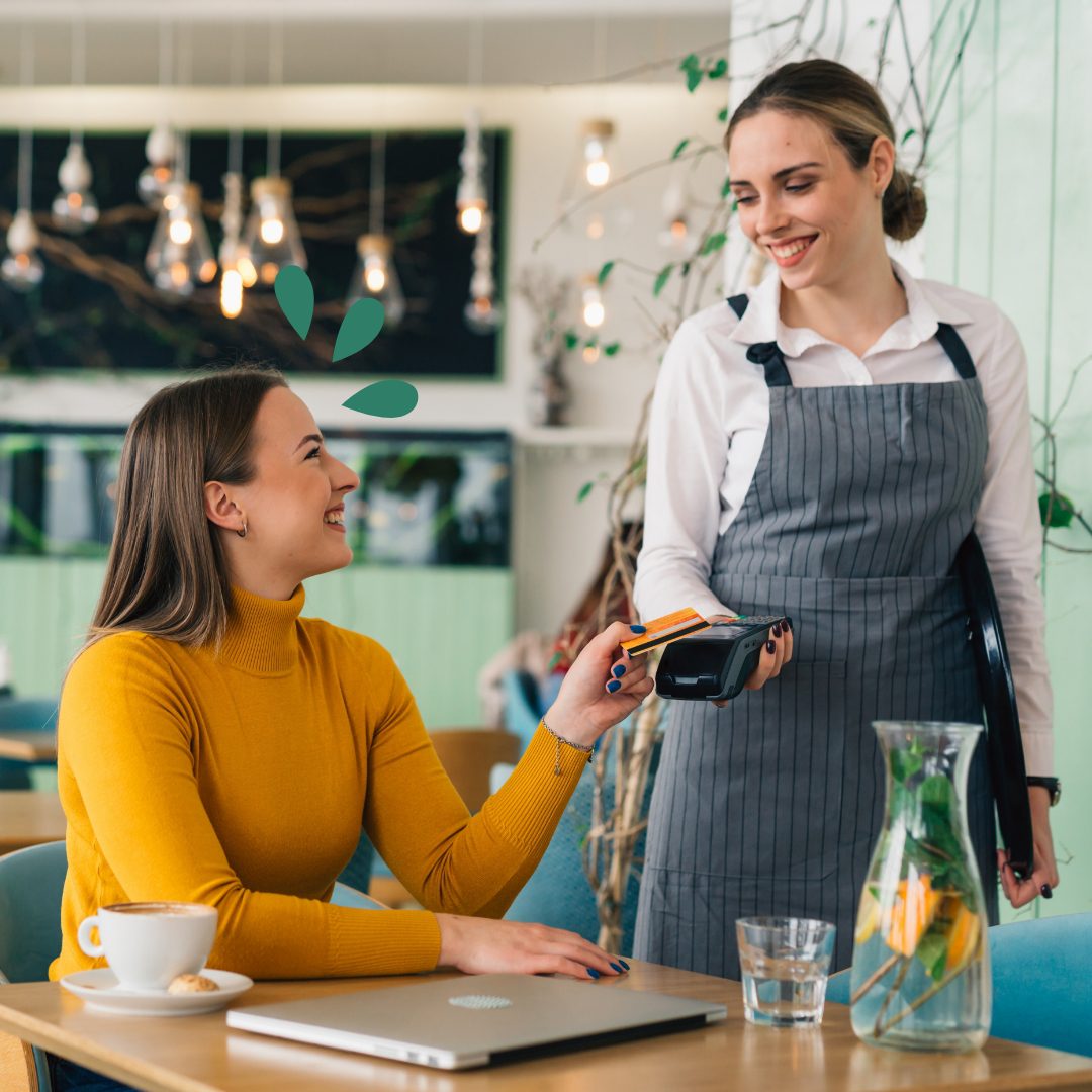 Tarjeta de débito VISA Mujer en una cafetería pagando su cuenta con tarjeta de débito.